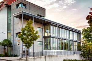 Außenansicht eines Bürogebäudes mit vielen Fenstern und Baum davor