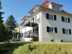 Großes weisse Haus mit Balkon von vorn